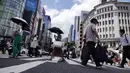 Orang-orang yang memakai masker untuk melindungi dari penyebaran virus corona berjalan di bawah terik matahari di distrik Perbelanjaan Ginza di Tokyo, Selasa (10/8/2021). (AP Photo/Eugene Hoshiko)