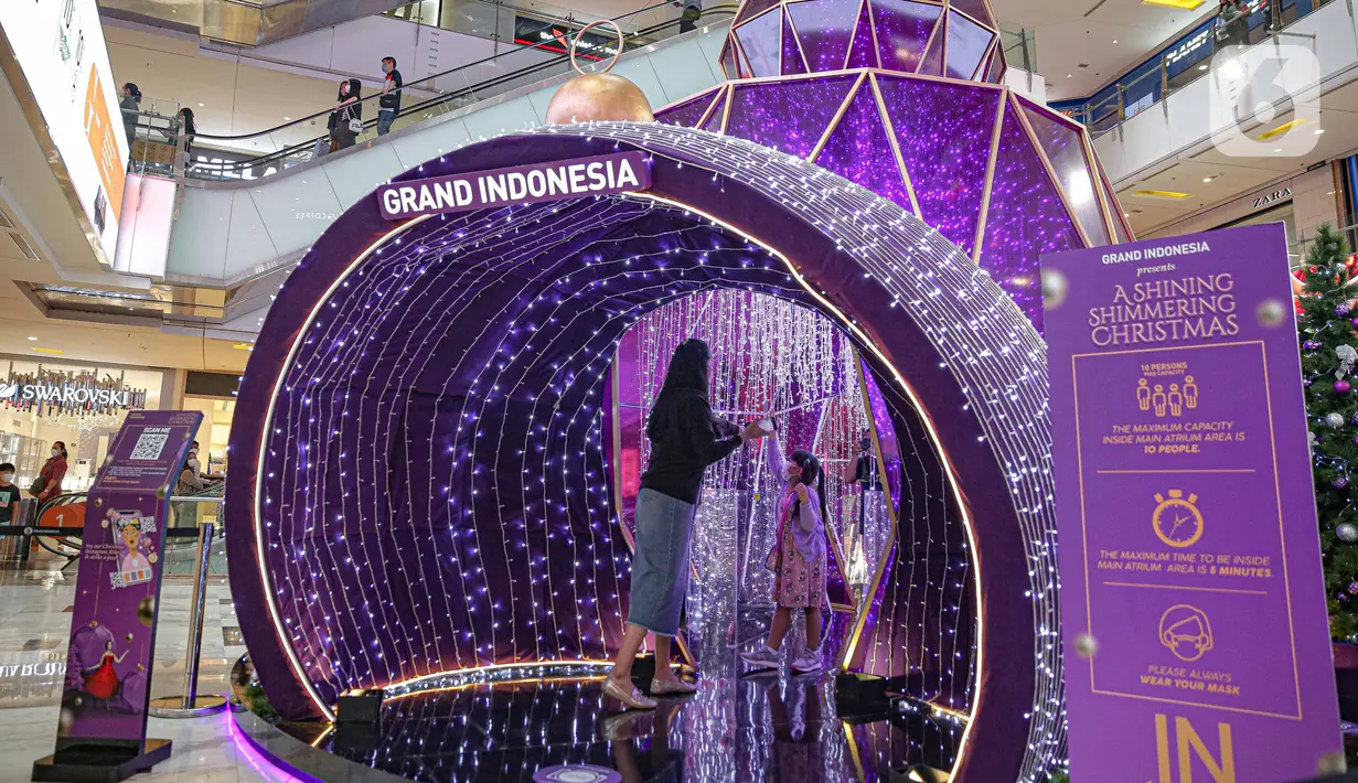 Pengunjung berada di dalam dekorasi perayaan Natal bertema "A Shining Shimmering Christmas" di Mal Grand Indonesia, Jakarta, Senin (13/12/2021). Dalam rangka menyambut Natal dan Tahun Baru, pusat perbelanjaan tersebut mempersembahkan “A Shining Shimmering Christmas”. (Liputan6.com/Faizal Fanani)