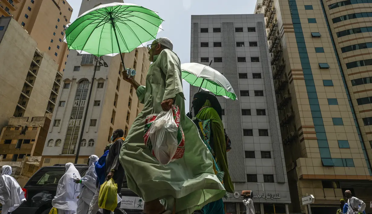 Jemaah haji menggunakan payung untuk melindungi diri dari terik matahari saat berjalan di kota suci Mekkah pada 23 Juni 2023.  (Photo by Sajjad HUSSAIN / AFP)