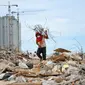 Seorang pria membawa sisa-sisa besi dari reruntuhan bangunan yang dirobohkan di kawasan Pasar Ikan, Penjaringan, Jakarta, Selasa (12/4). Selain warga, sejumlah pemulung besi berhambur untuk menjarah besi dari bekas bangunan (Liputan6.com/Yoppy Renato)