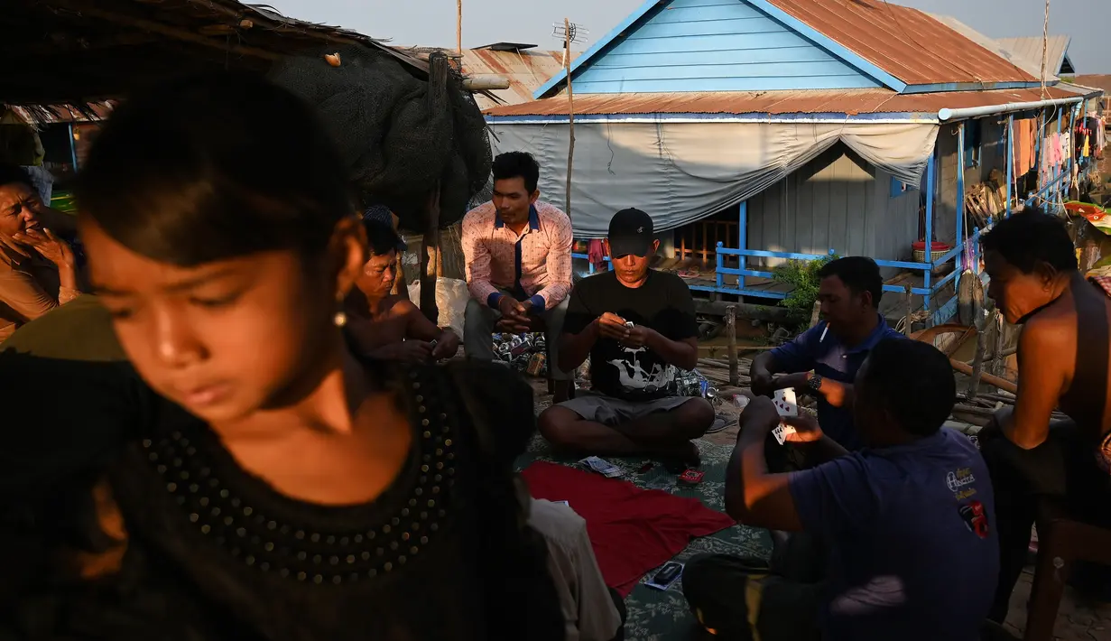 Para nelayan lokal bermain kartu di sebuah desa terapung di sepanjang sungai Siem Reap, Kamboja (5/12/2019). Desa Terapung Siem Reap adalah pintu gerbang ke danau air tawar terbesar di Asia Tenggara-Danau Tonle Sap. (AFP/Manan Vatsyayana)