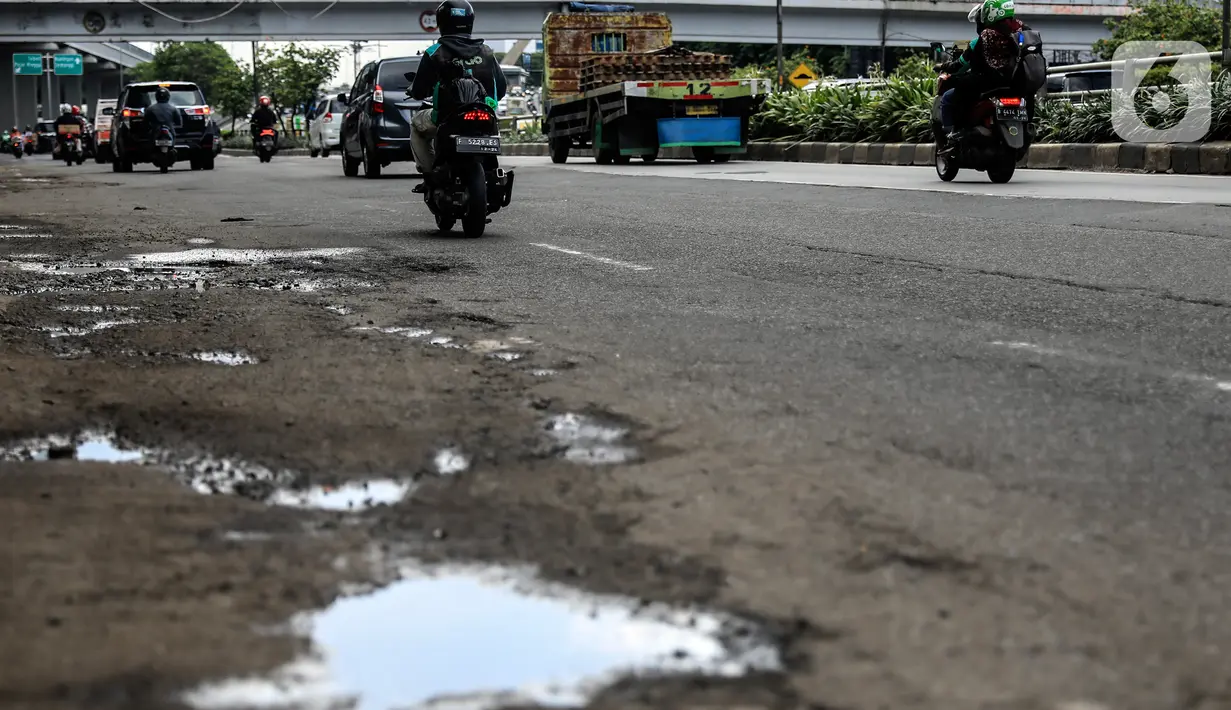 Sejumlah pengendara saat melintas dekat jalan yang berlubang di kawasan Gatot Subroto, Jakarta, Kamis (18/11/2021). Memasuki musim hujan yang turun hampir setiap hari membuat sejumlah ruas jalan rusak dan tergenang sehingga mengakibatkan jalan berlubang. (Liputan6.com/Johan Tallo)