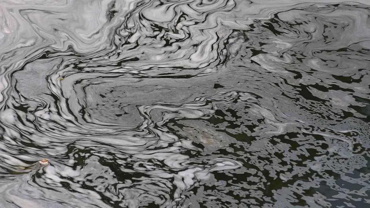 Busa putih yang berasal dari limbah deterjen tampak mengalir di Kanal Banjir Timur (KBT) setalah keluar dari pintu air Malaka Sari, Jakarta, Selasa (22/8/2023).