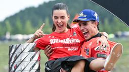 Pembalap Ducati Lenovo, Marc Marquez, bersama kekasihnya, Gemma Pinto, merayakan keberhasilan menjuarai MotoGP 2025 di Sirkuit Motegi, Jepang, Minggu (28/09/2025). (AFP/Toshifumi Kitamura)