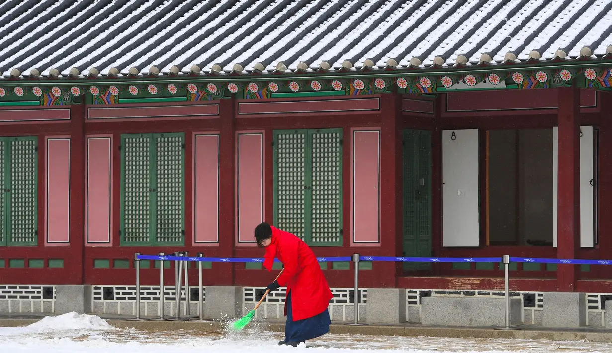 Seorang wanita mengenakan pakaian tradisional Korea "Hanbok" membersihkan salju di Istana Gyeongbok di Seoul, Korea Selatan (15/2). Istana Gyeongbok aslinya didirikan tahun 1394 oleh Jeong do jeon, seorang arsitek.  (AP Photo/Ahn Young-joon)