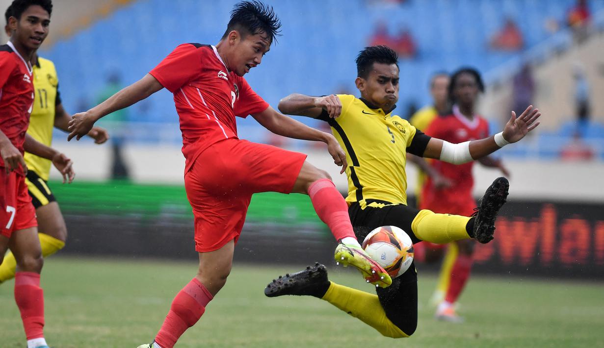 Gelandang Timnas Indonesia U-23, Witan Sulaeman berebut bola dengan bek Malaysia, Harith Haiqal bin Adam Afkar dalam pertandingan perebutan medali perunggu SEA Games 2021 di Stadion My Dinh, Minggu (22/5/2022). Indonesia ditahan imbang 1-1 dan menang 4-3 di adu penalti. (AFP/Ye Aung Thu)