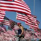 Seorang wanita berjalan diantara 3.000 bendera AS pada peringatan 15 tahun bagi para korban 11 September 2001 di Malibu, California, (11/09). Pengibaran bendera AS dilakukan sejak matahari terbit sampai terbenam. (REUTERS/Lucy Nicholso)
