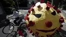 Seorang pria mengenakan masker untuk membantu mencegah penyebaran virus coronamengendarai sepeda melewati orang-orangan sawah yang menggambarkan virus corona yang ditampilkan di Tokyo, Senin (28/9/2020). Jepang mengonfirmasi lebih dari 70 kasus virus corona. (AP Photo/Eugene Hoshiko)