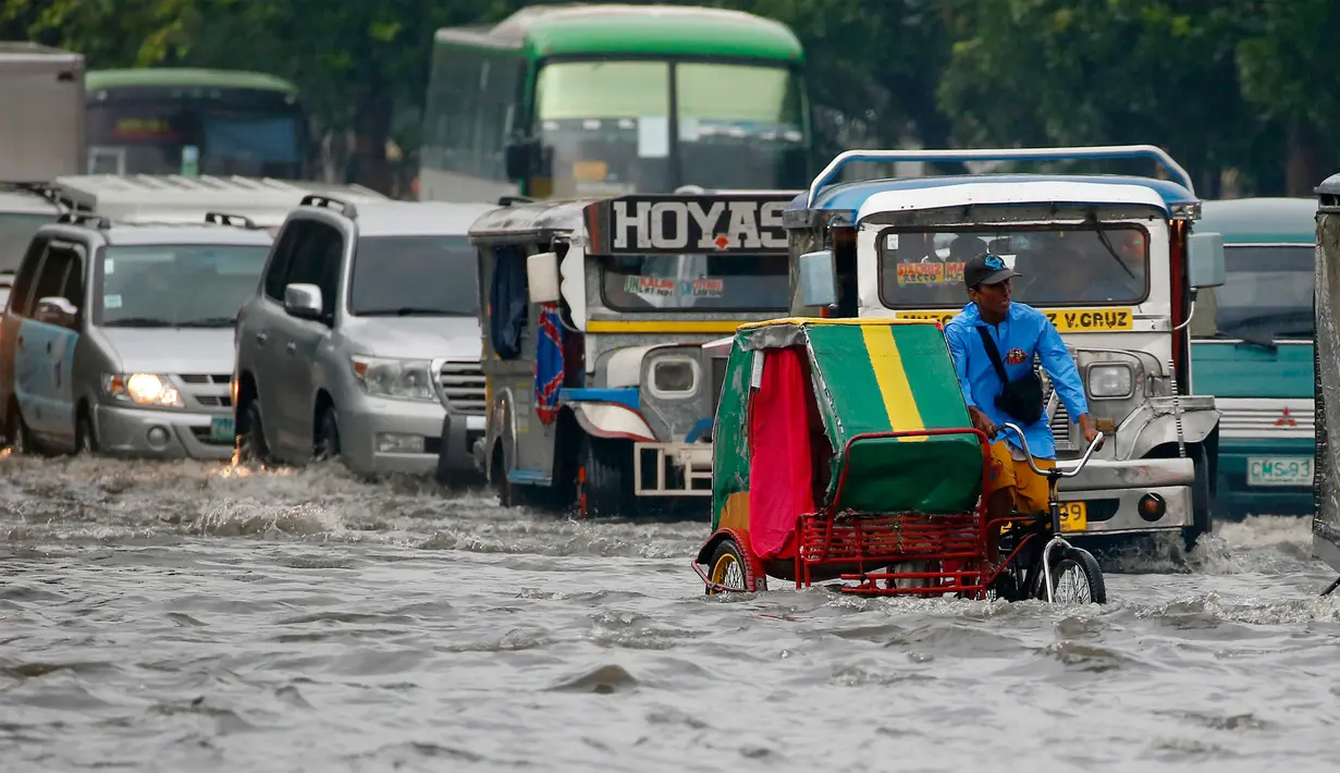 Pengendara becak menerjang genangan air di salah satu wilayah Manila, Filipina, Kamis (27/7). Banjir menggenangi beberapa wilayah Kota Metropolitan setelah hujan lebat yang diakibatkan oleh badai tropis ‘Nesat’. (AP/Bullit Marquez)