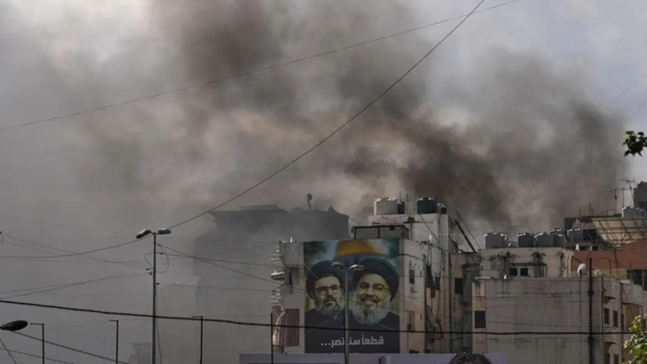 Potret pemimpin lama Hizbullah, Hassan Nasrallah (kanan), dan sepupunya, Hashem Safieddine, terlihat di tengah kepulan asap akibat serangan udara Israel di wilayah Dahiyeh, pinggiran selatan Beirut, Lebanon, Senin, 30 Maret 2026.