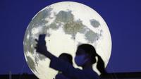 Warga berswafoto dekat instalasi bulan purnama yang bersinar di sebuah taman di Seoul, Korea Selatan, Jumat (18/9/2020). Pejabat setempat memasang bulan purnama buatan untuk meningkatkan semangat saat wabah COVID-19 sekaligus menyambut Chuseok, Thanksgiving versi Korea. (AP Photo/Ahn Young-joon)