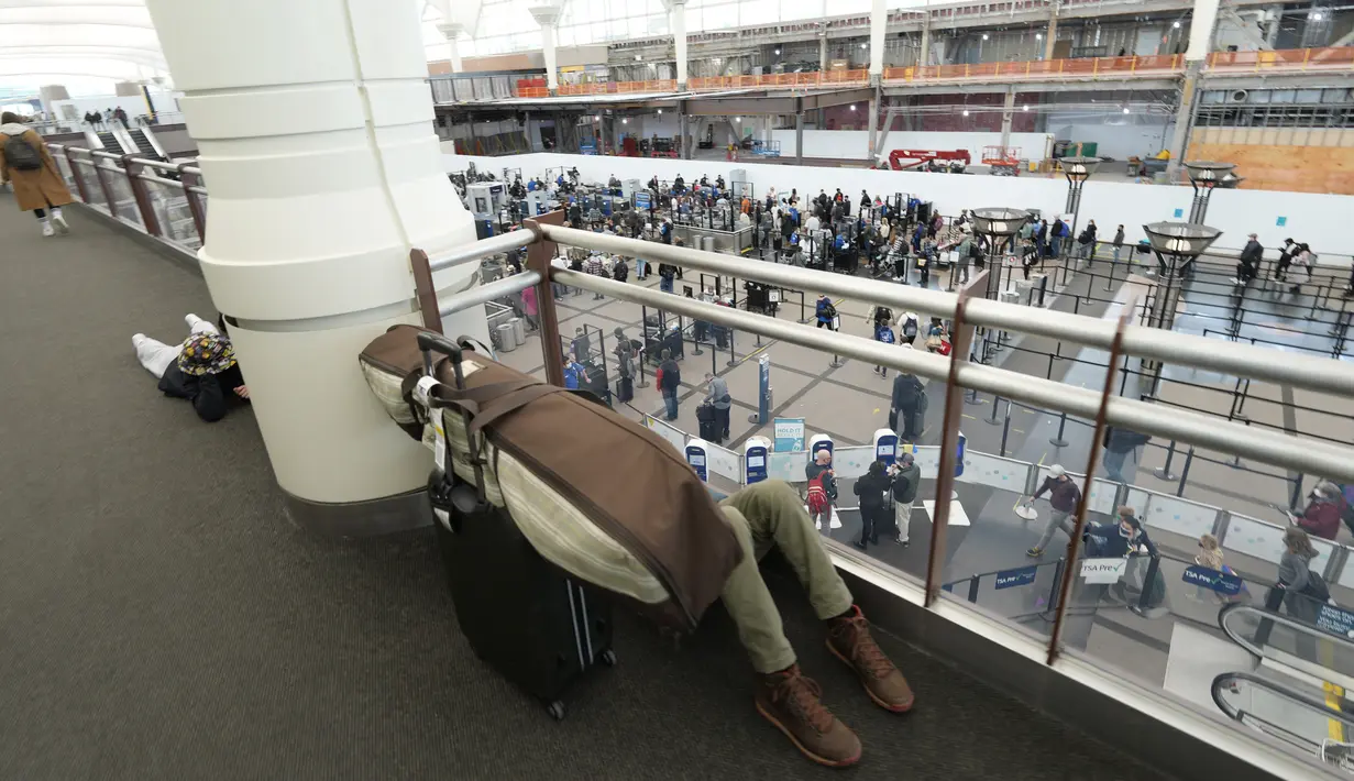 Penumpang tidur di tengah barang bawaannya di atas pos pemeriksaan Bandara Internasional Denver di Denver, AS, Senin (3/1/2022). Badai musim dingin ditambah pandemi membuat frustrasi pelancong yang penerbangan pulang dari liburannya dibatalkan atau ditunda di awal tahun. (AP Photo/David Zalubowski)