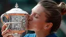 Petenis Rumania, Simona Halep mencium trofi Grand Slam seusai menang atas petenis AS, Sloane Stephens pada babak final Prancis Terbuka 2018 di stadion Roland Garros, Sabtu (9/6). Halep berhasil meraih gelar grand slam pertamanya. (AP/Alessandra Tarantino)