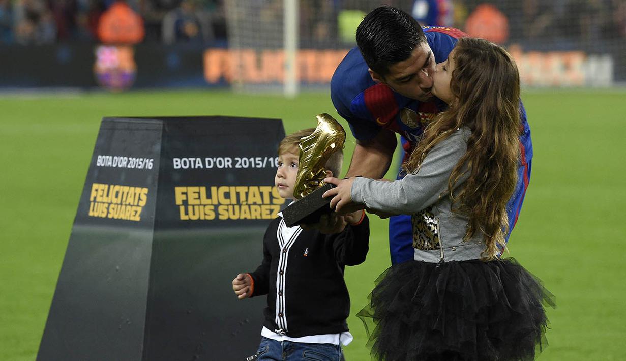 Striker Barcelona, Luis Suarez, mencium putrinya saat menunjukan Sepatu Emas jelang laga La Liga melawan Granada di Stadion Nou Camp, Spanyol, Sabtu (29/10/2016). Suarez meraih gelar ini usai mencetak 40 gol pada musim lalu. (AFP/Lluis Gene)