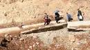 Orang-orang yang melarikan diri dari invansi militer Israel di Lebanon menyeberangi sebuah kawah, yang disebabkan oleh serangan Israel, di daerah Masnaa, salah satu wilayah yang berbatasan langsung dengan Suriah, pada 20 November 2024. (Anwar AMRO/AFP)
