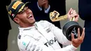 Pemabalap Mercedes Lewis Hamilton memegang pialanya diatas podium usai berhasil menjuarai Grand Prix di Monaco, (29/5). Hamilton menjadi yang tercepat dengan mencatatkan waktu satu jam 59 menit 29,133 detik. (REUTERS/Eric Gaillard)