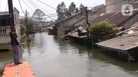 Warga melintasi jembatan apung saat banjir melanda perumahan Periuk Damai, Tangerang, Banten, Selasa (22/2/2021). Banjir setinggi 2,5 meter tersebut sudah terjadi selama 4 hari. (Liputan6.com/Angga Yuniar)