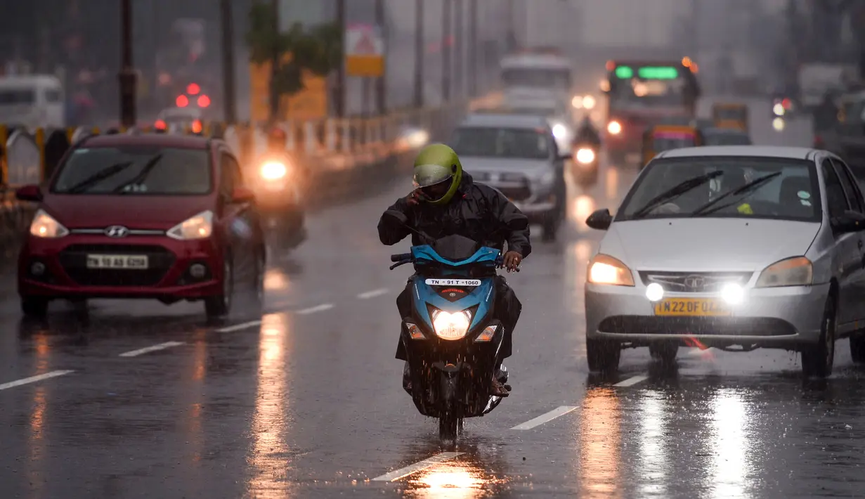 Seorang pengendara sepeda motor berkendara di sepanjang jalan di bawah hujan lebat di Chennai ketika topan Nivar mendekati pantai tenggara negara itu, (25/11/2020). (AFP/Arun Sankar)