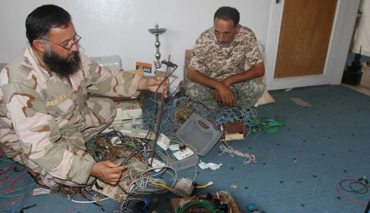 Anggota militer Libya menjinakkan bom rakitan milik militan ISIS di Sirte (5/9). Setelah berhasil menaklukkan salah satu markas ISIS, Militer Libya menemukan bom rakitan dan senjata peledak lainnya yang masih aktif. (REUTERS/Hani Amara)
