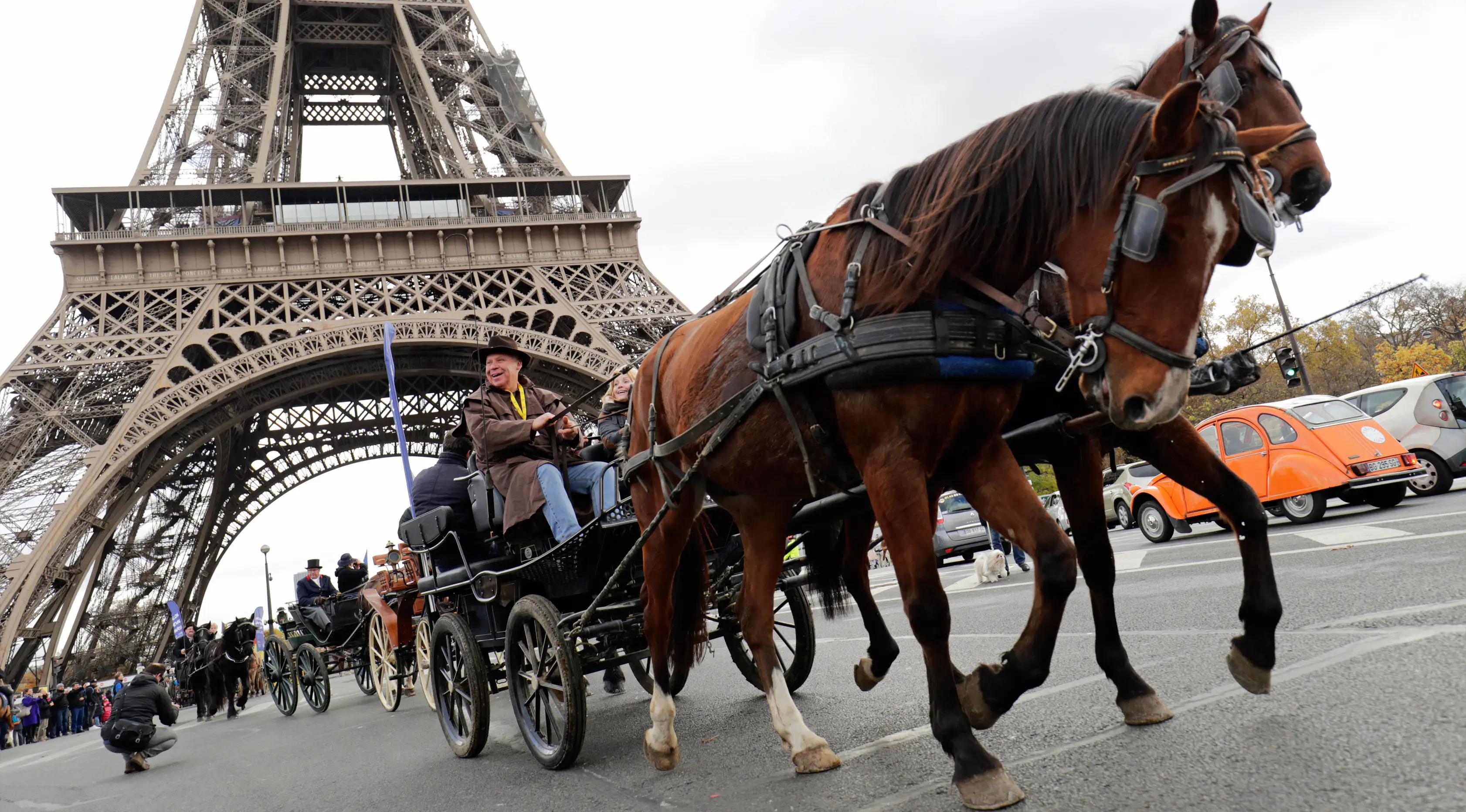 Sejumlah orang mengendarai kereta kuda melintas di depan Menara Eiffel saat mengikuti parade kuda ke-20 di Paris, Prancis (19/11). (AFP Photo/Thomas Samson)