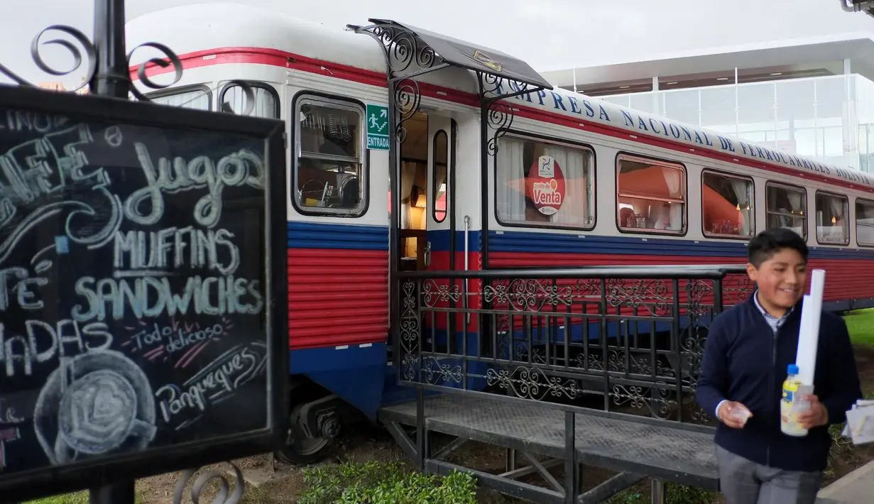 Seorang anak laki-laki melintas dekat sebuah kafe yang dibangun dari gerbong kereta tua yang tak terpakai di La Paz, Bolivia pada 15 Maret 2019. Selain dimanfaatkan sebagai kafe, bagian gerbong kereta juga dijadikan toko. (David Mercado/Reuters)