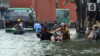 Pengendara sepeda motor mendorong kendaraannya melewati banjir rob di kawasan Pelabuhan Sunda Kelapa, Jakarta, Selasa (7/12/2021). Banjir rob setinggi satu meter memutus Jalan Kerapu yang menghubungkan Ancol-Pluit. (merdeka.com/Arie Basuki)