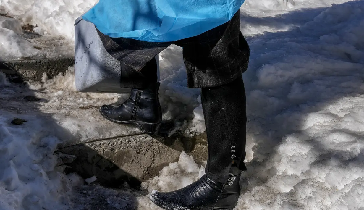 Masrat Farid, seorang petugas kesehatan yang mengenakan sepatu bot kulit, berdiri di atas tangga yang tertutup salju selama upaya vaksinasi COVID-19 di Gagangeer, timur laut Srinagar, Kashmir yang dikuasai India, pada 12 Januari 2022. (AP Photo/Dar Yasin)