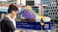 Warga berfoto di depan Tugu Sepatu, Sudirman, Jakarta, Minggu (19/9/2021). Tugu Sepatu menjadi sasaran pencoretan dengan semprotan aerosol oleh orang tak dikenal sehari usai diresmikan pada 17 September 2021. (Liputan6.com/Faizal Fanani)