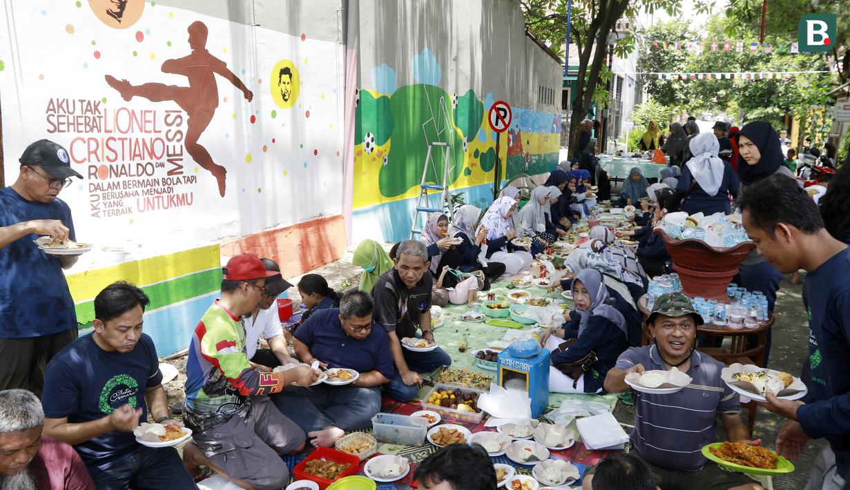 Warga makan bersama usai bergotong-royong menghias kampung bertema Piala Dunia 2022 di Perum Depok Maharaja Blok M1 Cluster Cemara, Rangkapan Jaya, Depok, Jawa Barat, Minggu (30/10/2022). (Bola.com/M Iqbal Ichsan)