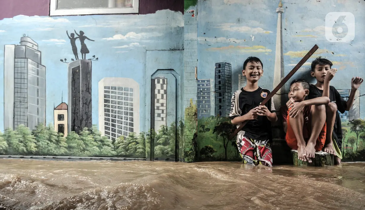 Anak-anak bermain air saat banjir merendam permukiman di Kebon Pala, Jakarta, Senin (8/2/2021). Hujan deras yang mengguyur Ibu Kota dan wilayah Bogor menyebabkan permukiman di Kebon Pala terendam banjir sejak Minggu (7/2/2021) sore. (merdeka.com/Iqbal S. Nugroho)