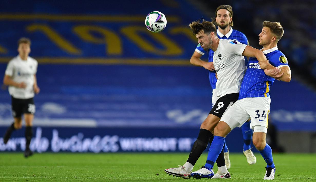 Bek Brighton, Joel Veltman, berebut bola dengan striker Portsmouth, John Marquis, pada laga Piala Inggris di Falmer Stadium, Jumat (18/9/2020) dini hari WIB. Brighton menang 4-0 atas Portsmouth. (AFP/Glyn Kirk/pool)