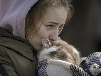 Seorang wanita yang dievakuasi dari Irpin menangis mencium kucing yang dibungkus selimut di titik triase di Kyiv, Ukraina, 11 Maret 2022. Dalam eksodus lebih dari 2,5 juta orang yang melarikan diri dari invasi Rusia, terdapat hewan peliharaan yang tidak dapat ditinggalkan. (AP Photo/Vadim Ghirda)