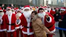 Seorang turis berfoto bersama dengan orang berpakaian seperti Santa Claus saat acara amal Natal di pusat kota Seoul, Korea Selatan, (24/12/2015). (REUTERS/Kim Hong-Ji)