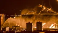 Air disemprotkan oleh pemadam kebakaran ke arah asap dan api yang membubung dari fasilitas minyak Aramco menyusul laporan serangan pemberontak Yaman di Jeddah, Arab Saudi, 25 Maret 2022. Pemberontak Yaman mengatakan mereka menyerang fasilitas minyak Arab Saudi tersebut. (AFP)