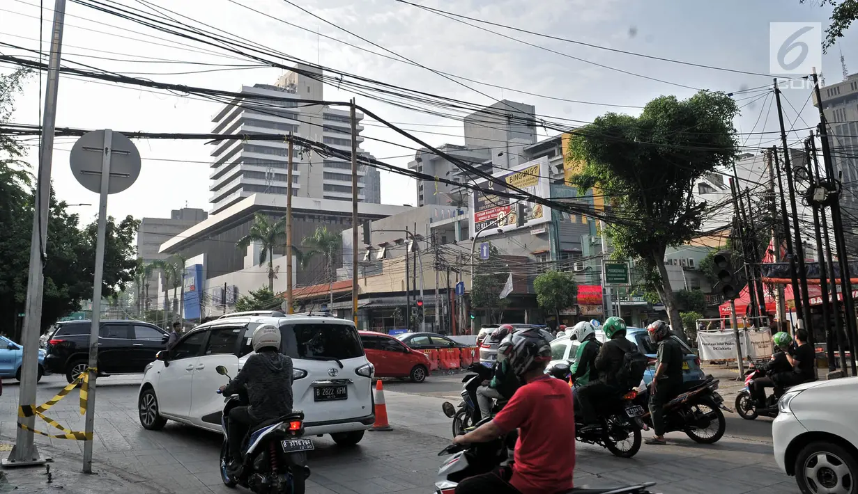 Kendaraan saat melintasi bambu penyangga kabel di Jalan Wahid Hasyim, Jakarta, Selasa (6/11). Dua buah bambu penyangga kabel tersebut mengganggu kenyamanan dan mengancam keselamatan pengguna jalan. (Merdeka.com/Iqbal S. Nugroho)