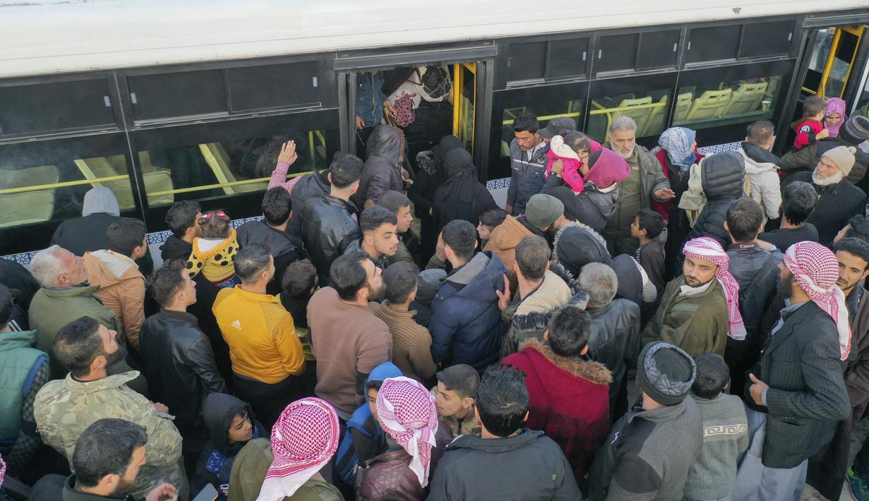 Foto udara menunjukkan pengungsi Suriah yang tinggal di Turki menunggu untuk naik bus melalui penyeberangan perbatasan Bab al-Hawa utara, pada 17 Februari 2023, saat mereka kembali ke Suriah setelah gempa bumi yang mematikan. Perubahan aturan yang dirancang untuk menyatukan kembali keluarga di kedua sisi perbatasan yang dilanda bencana 6 Februari, yang telah menewaskan lebih dari 41.000 orang dan membuat jutaan orang mengungsi di kedua negara. (AFP/Omar Haj Kadour)