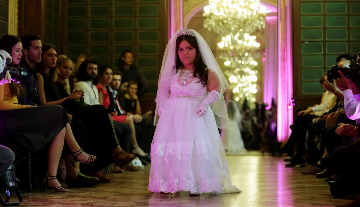 Seorang model berjalan di atas catwalk menampilkan gaun khusus perempuan bertubuh pendek dalam International Dwarf Fashion Show di Paris, Selasa (26/9). Melalui ajang, mereka ingin mendobrak standar kecantikan yang diskriminatif. (Thomas SAMSON/AFP)