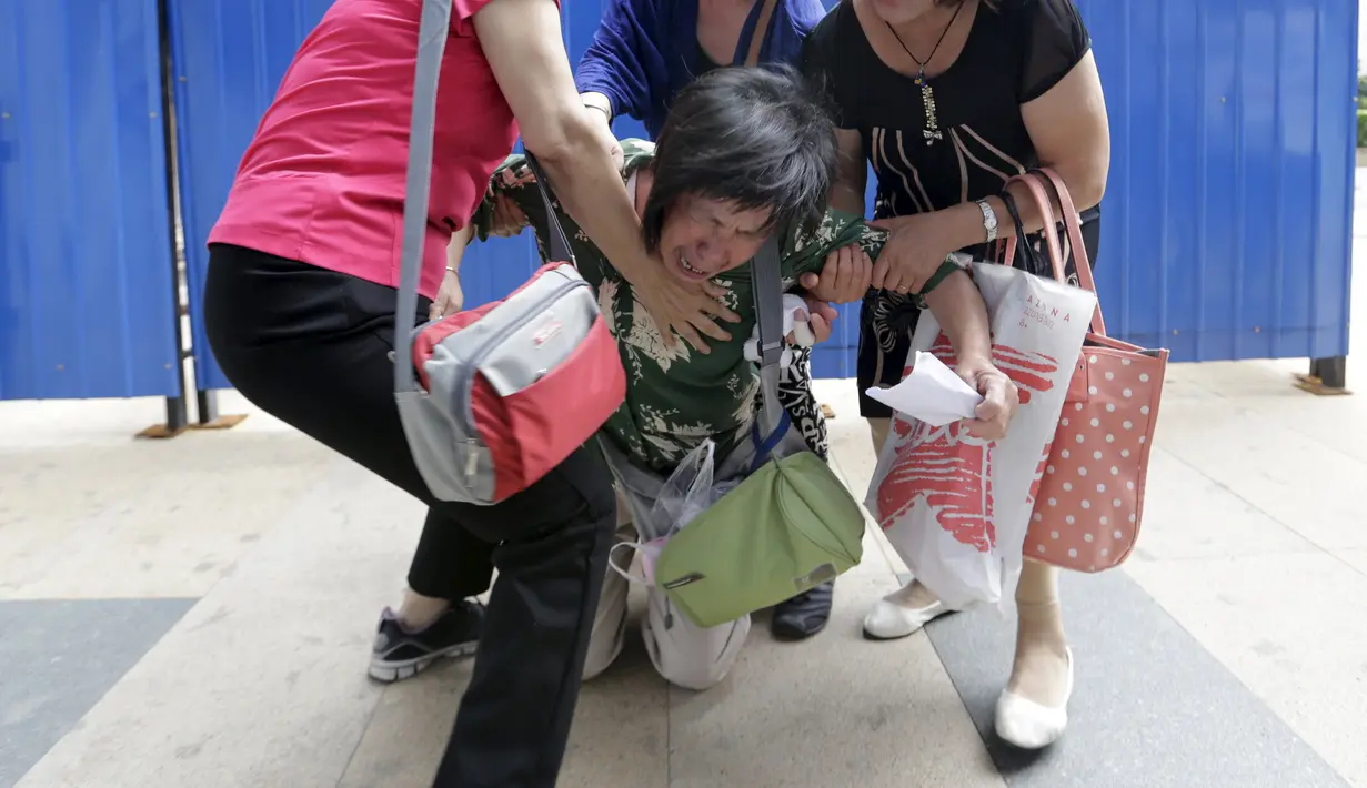 Bao Lanfang (tengah), ibu dari salah satu penumpang MH370 berlutut saat menyuarakan tuntutannya kepada Malaysia Airlines, Beijing, Kamis (6/8). (REUTERS/Jason Lee)