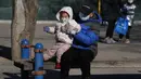 Seorang pria mengangkat seorang anak di sebuah taman di Beijing, China (13/1/2022). Jumlah bayi yang lahir di China terus menyusut tahun lalu, seiring menyusutnya jumlah tenaga kerja. (AP Photo/Andy Wong)