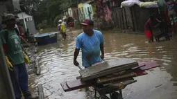 Warga membersihkan rumah mereka yang terendam banjir di Itapetinga, negara bagian Bahia, Brasil, Selasa (28/12/2021). Banjir menyebabkan ribuan orang terpaksa mengungsi dari rumah mereka . (AP/Raphael Muller)