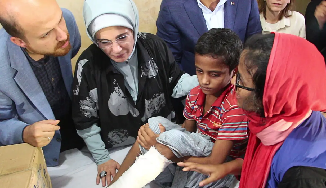 Ibu Negara Turki, Emine Erdogan dan putranya, Bilal melihat luka seorang muslim Rohingya yang melarikan diri dari Myamnar saat menyerahkan bantuan di kamp pengungsi Kutupalong, Bangladesh, Kamis (7/9). (Presidency Press Service via AP, Pool)
