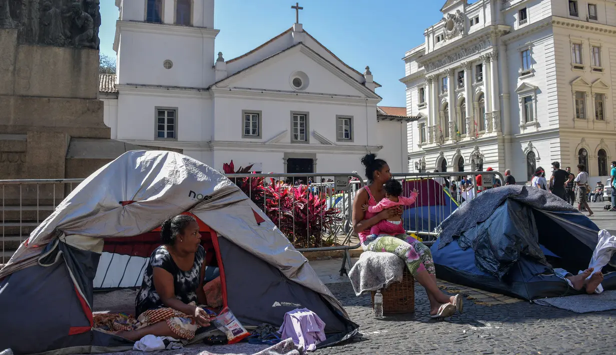Sebuah keluarga tunawisma terlihat di tenda-tenda yang didirikan di Patio do Colegio, pusat kota Sao Paulo, Brasil, pada 19 Agustus 2021. Sao Paulo menghadapi krisis tunawisma, karena harga baru-baru ini menjadi beban yang terlalu berat bagi populasi yang semakin miskin. (NELSON ALMEIDA / AFP)