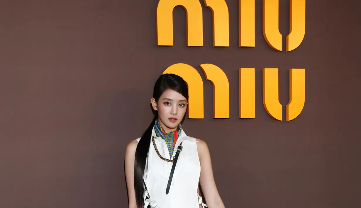 Berbeda dari Momo, Minnie I-DLE tampil lebih sleek dan modern. Ia memadukan cropped vest putih dengan rok midi suede berwarna olive yang memberi nuansa earthy.  Tas suede cokelat dan sepatu pointed heels memperkuat kesan sophisticated, sementara scarf bermotif di leher memberikan aksen kecil yang membuat keseluruhan look terasa lebih dinamis. [Dok/Miu Miu].