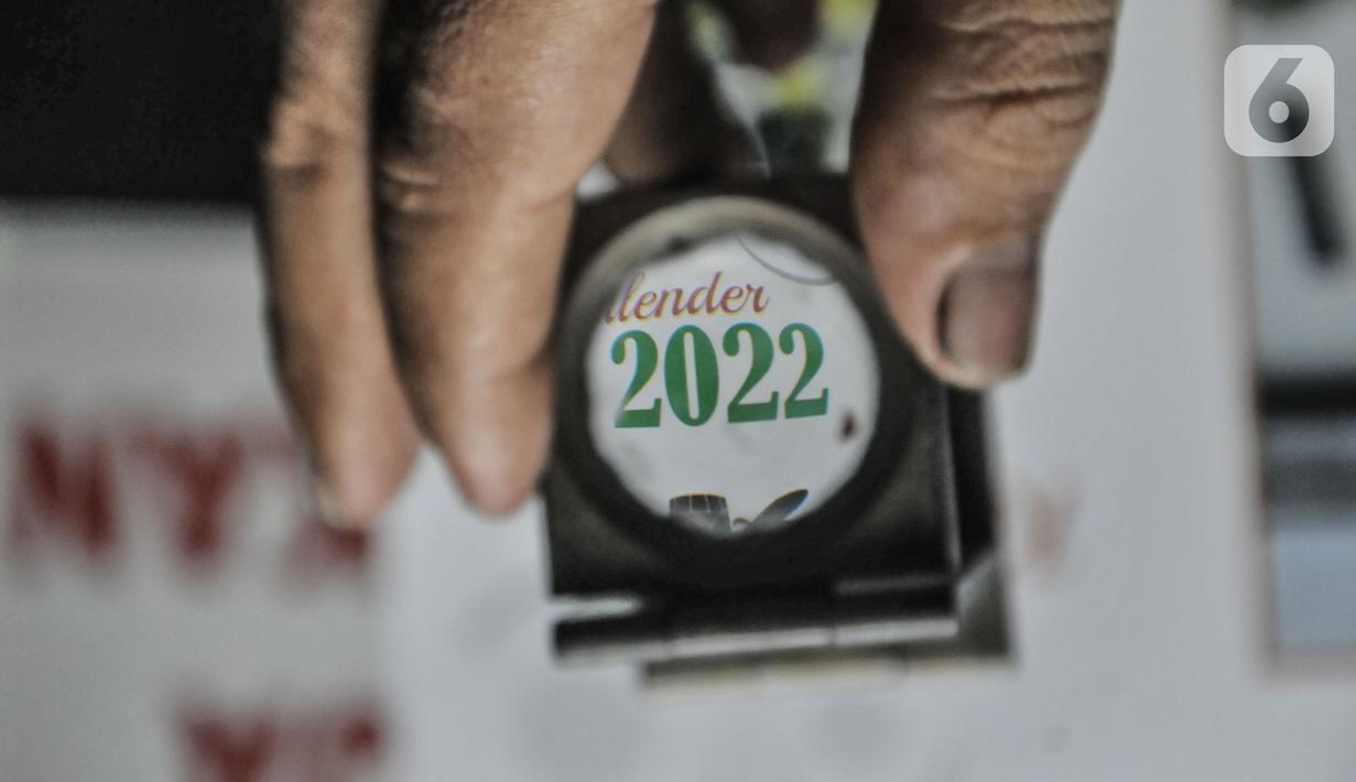 Pekerja menggunakan kaca pembesar untuk memeriksa hasil cetakan kalender di toko percetakan kawasan Senen, Jakarta, Senin (27/12/2021). Jelang tahun baru 2022 permintaan kalender meningkat hingga 20 persen dibandingkan tahun sebelumnya. (merdeka.com/Iqbal S Nugroho)