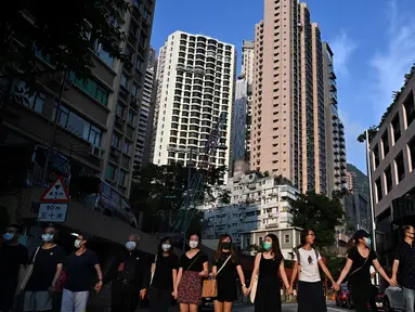 Para siswa, alumni dan guru membentuk rantai manusia di area Mid-Levels, Hong Kong, Senin (9/9/2019). Aksi dilakukan para siswa yang masih berseragam sekolah sambil memakai masker sebagai bentuk dukungan terhadap demonstran anti pemerintah setelah bentrokan pada akhir pekan. (Anthony WALLACE/AFP)