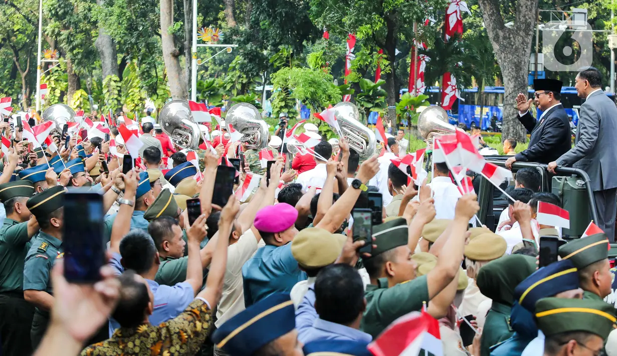 Lambaian tangan dan bendera Merah Putih mengiringi perjalanan Presiden Republik Indonesia Prabowo Subianto ke Istana Negara. (Liputan6.com/Herman Zakharia)