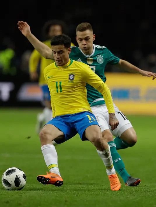 Pemain timnas Brasil,  Coutinho berebut bola dengan pemain timnas Jerman, Joshua Kimmich dalam laga uji coba di Olympiastadion Berlin, Selasa (27/3). Brasil sukses menaklukkan Jerman dengan skor 1-0. (AP Photo/Michael Sohn)