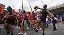 Sebuah pesta pora menari dengan para pemain selama Karnaval Notting Hill tahunan di London barat, Senin (29/8/2022). Karnaval yang kembali ke jalanan untuk pertama kalinya dalam dua tahun, setelah digagalkan oleh pandemi, adalah salah satu perayaan festival terbesar dari jenisnya di Eropa. (AP Photo/Alberto Pezzali)