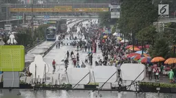 Sejumlah warga memadati kawasan Bunderan HI saat kegiatan rutin hari bebas kendaraan bermotor atau car free day (CFD), Jakarta, Minggu (4/2). Walaupun gerimis mengguyur kawasan Bunderan HI tetap ramai oleh aktivitas warga. (Liputan6.com/Faizal Fanani)