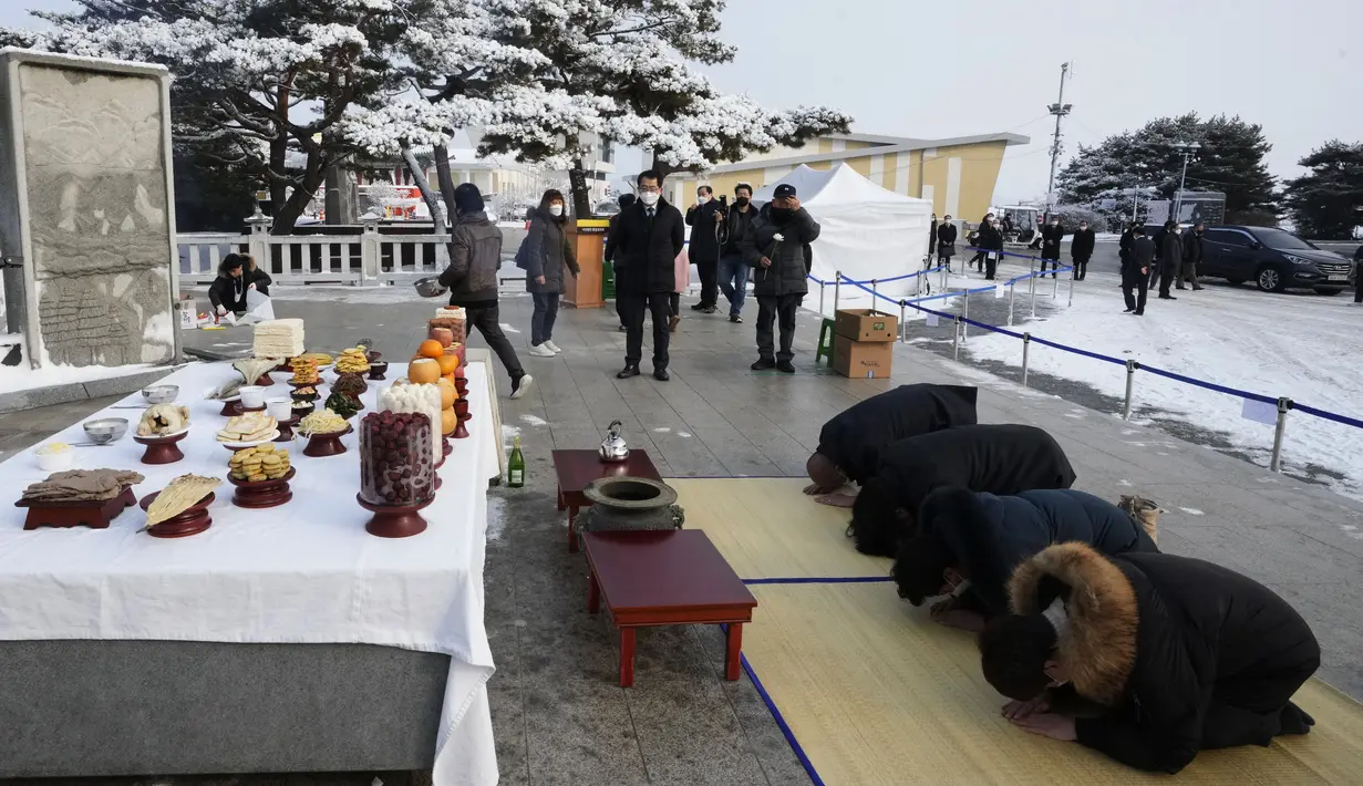 Pengungsi Korea Utara dan anggota keluarganya membungkuk memberikan penghormatan kepada leluhur mereka untuk merayakan tahun Baru Imlek saat mengunjungi Paviliun Imjingak dekat perbatasan dengan Korea Utara, di Paju, Korea Selatan, Selasa (1/2/2022). (AP Photo/Ahn Young-joon)